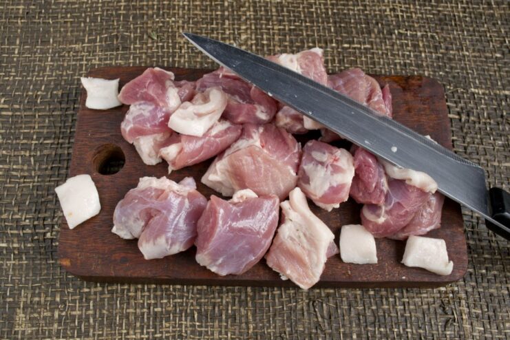Close-up of cubed raw pork and pork fat on a cutting board, ready for mincing.