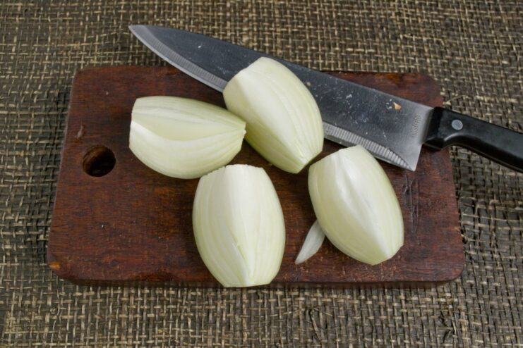 Coarsely chopped yellow onion on a cutting board, an optional step before adding to the mince.