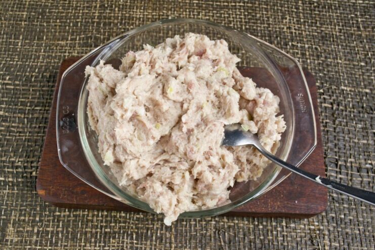 A food processor bowl containing freshly ground pork, fat, and onion mince.