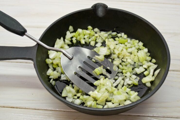 Sautéing onions and garlic to build the flavor base for the sauce. Chopped onions and garlic being sautéed in a skillet with olive oil.