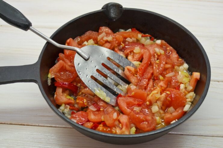 Simmering fresh tomatoes to create a rich and natural sauce base. Diced fresh tomatoes being added to the skillet with onions and chili to simmer.