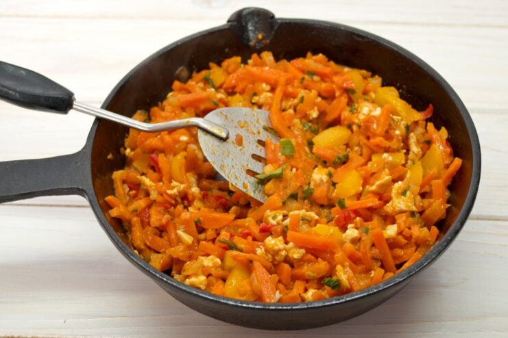 Finishing the sauce with bell peppers, herbs, and spices for maximum flavor. Diced bell peppers and fresh herbs being added to the chicken and vegetable sauce.