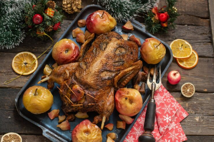 A whole roasted duck with apples served on a platter.