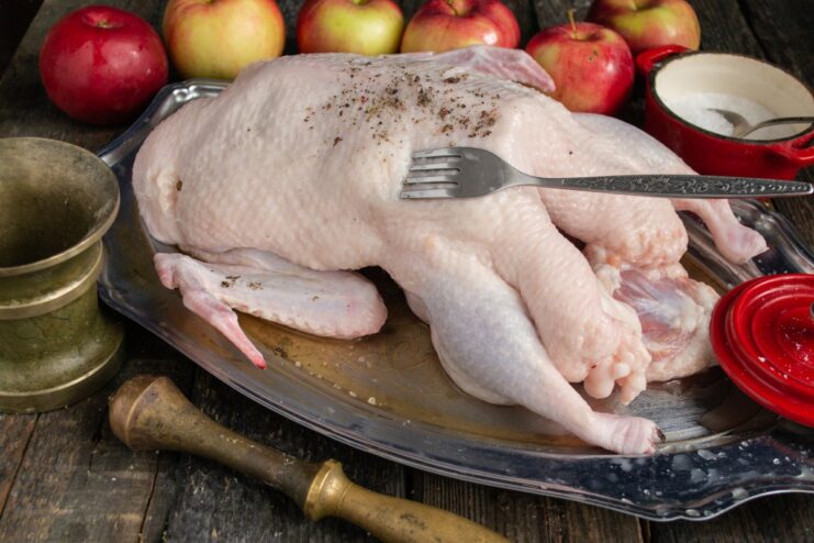 How to Prepare and Season a Duck for Roasting Raw duck being seasoned with salt and pepper before roasting.