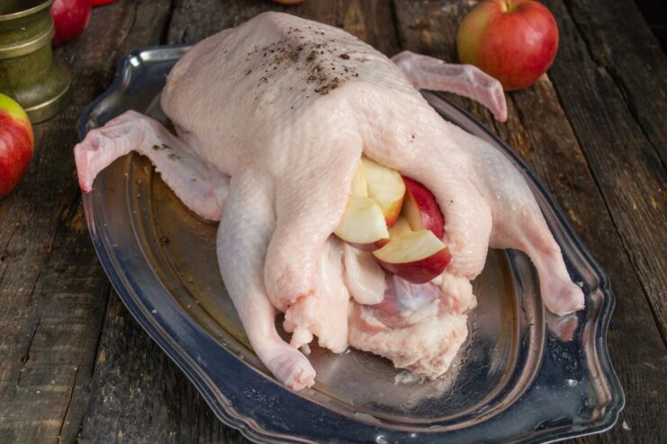 Step-by-Step: Stuffing the Duck with Apples Stuffing the cavity of a raw duck with apple slices.
