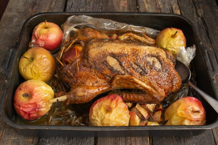 How to Get Crispy Skin on a Roast Duck Roasted duck in an opened roasting bag, surrounded by apples, ready for broiling.