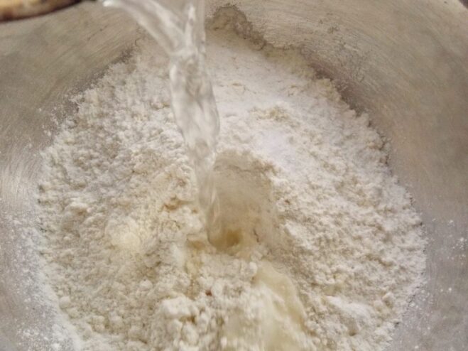 Making the special hot water dough for tender vareniki. Kneading the soft and elastic dough for vareniki in a bowl.
