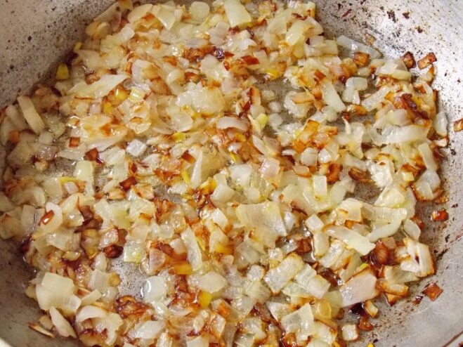 Frying diced onions until golden brown for the vareniki filling. Diced onions being sautéed in a frying pan until golden.
