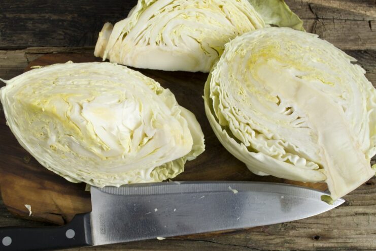 Cutting Cabbage into Wedges. Be sure to leave part of the core intact to hold the leaves together. Halved cabbage being cut into smaller wedges, with the core partially intact.