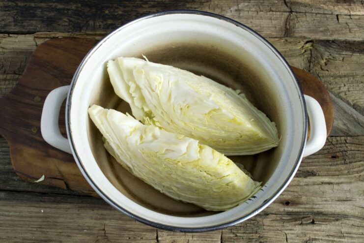 Boiling the Cabbage Wedges. The cabbage is placed in a pot and covered with boiling water and salt. Cabbage wedges in a saucepan being covered with boiling water.