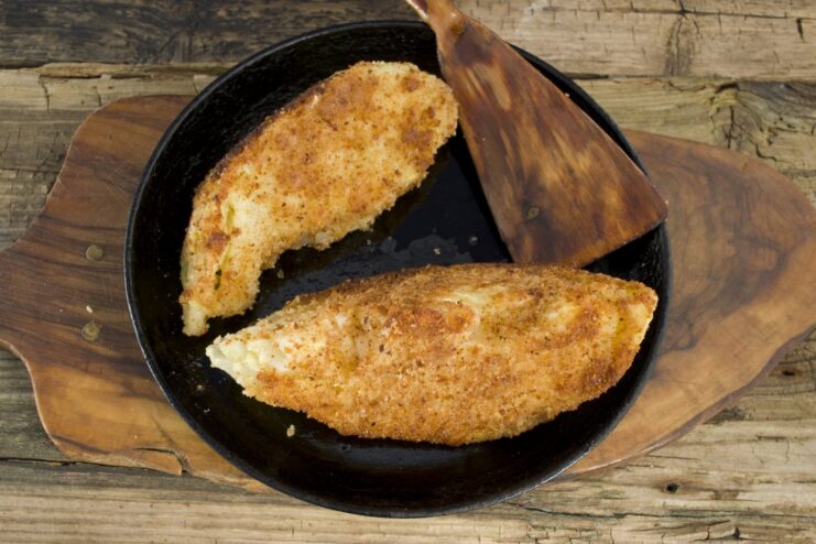 Frying to Perfection. Cook on each side until you achieve a beautiful golden-brown and crispy crust. Three breaded cabbage schnitzels frying to a golden-brown color in a pan with oil.
