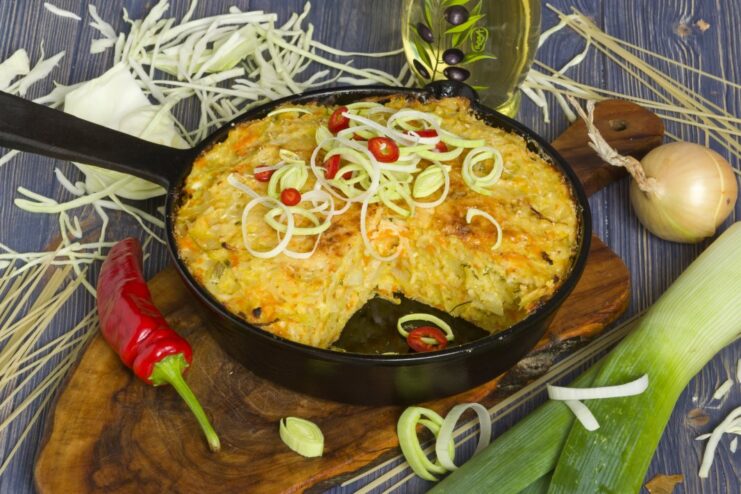 A slice of baked pasta casserole with tvorog and cabbage on a plate, garnished with herbs.
