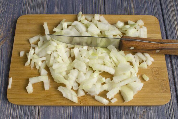 Step 1: Sautéing Finely Chopped Onion Until Golden Finely chopped onion being sautéed in a skillet with oil.