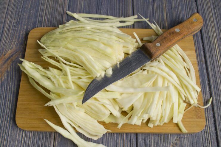 Step 3: Stewing Shredded Cabbage with Onions and Carrots Shredded white cabbage being stewed with onions and carrots in a pan.