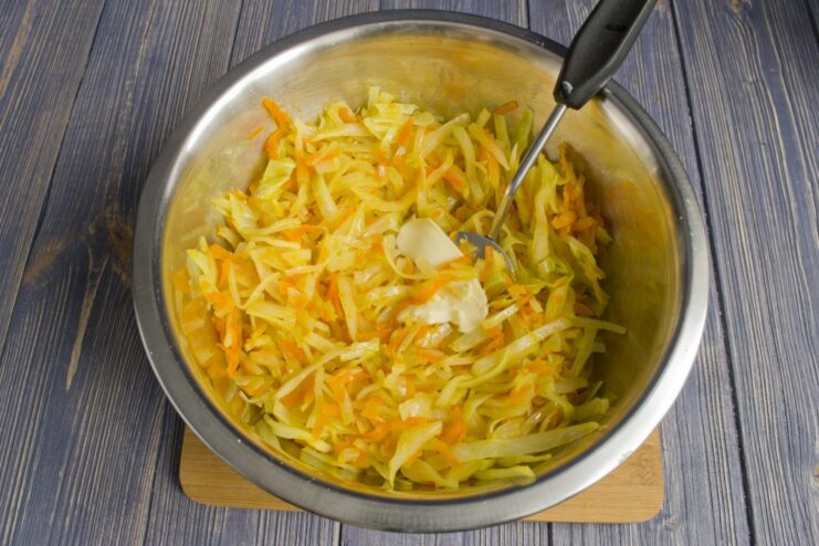 Preparing the Filling: Combining Stewed Vegetables with Butter A bowl containing stewed cabbage, carrots, and onions mixed with a pat of butter.