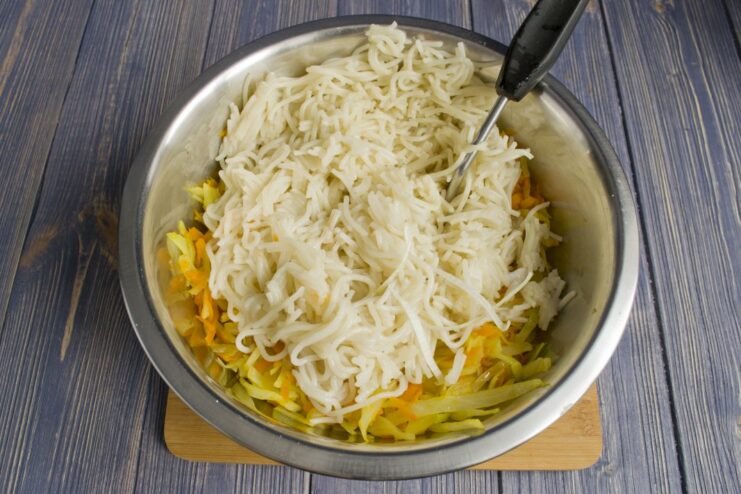 Combining Pasta and Vegetables for the Casserole Cooked spaghetti being added to the bowl of stewed vegetables.