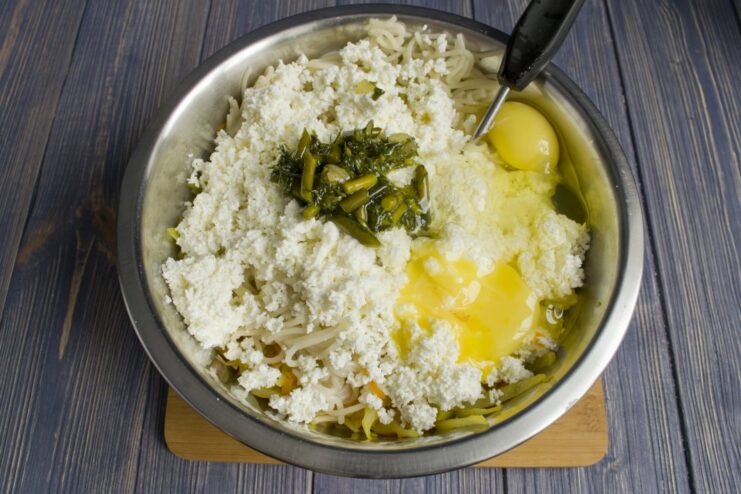 Binding the Casserole: Adding Eggs to the Mixture Two raw eggs cracked into the bowl with the casserole mixture.