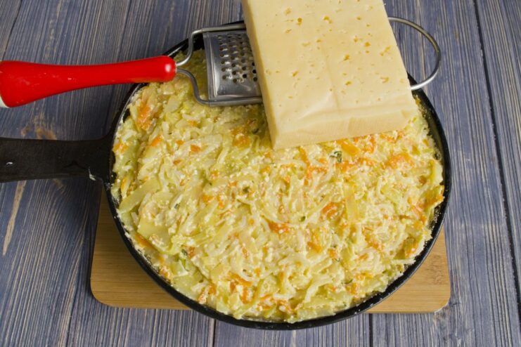 Preparing the Cheesy Topping: Finely Grating Hard Cheese A block of hard cheese being finely grated.