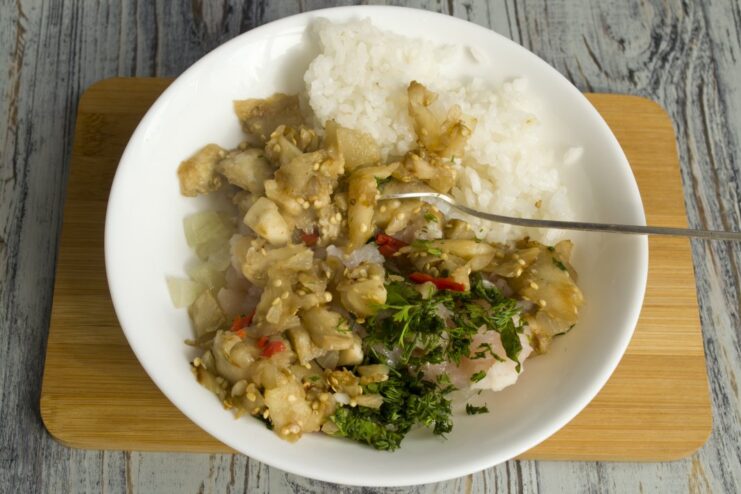 No Waste: Adding Sautéed Eggplant Flesh to the Filling Sautéed eggplant cubes being added to the rice and chicken mixture in a bowl.