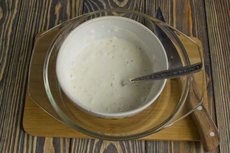 Preparing the creamy Stroganoff sauce by mixing smetana (sour cream) and flour. A white bowl containing a creamy white sauce made from smetana and flour.