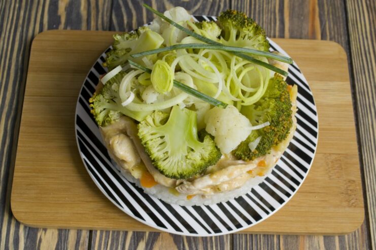 The final dish: Assembling the plate with rice, Chicken Stroganoff, and steamed veggies. A finished plate of Chicken Stroganoff over rice, with steamed broccoli and cauliflower on the side.