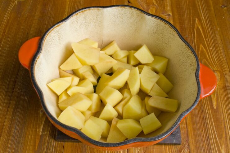 Step 1: Sautéing the Potatoes for the Stew Base Chopped potatoes being added to a hot braising pan with oil.
