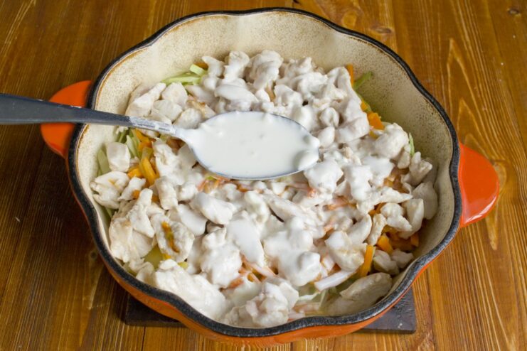 Creating the Creamy Sauce with Smetana A creamy smetana-based sauce being poured over the chicken and vegetables.