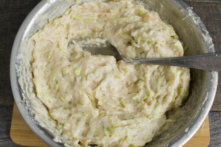 Mixing the ground chicken, zucchini, and seasonings together to form the patty mixture. A bowl of the complete chicken patty mixture being mixed with a spoon.