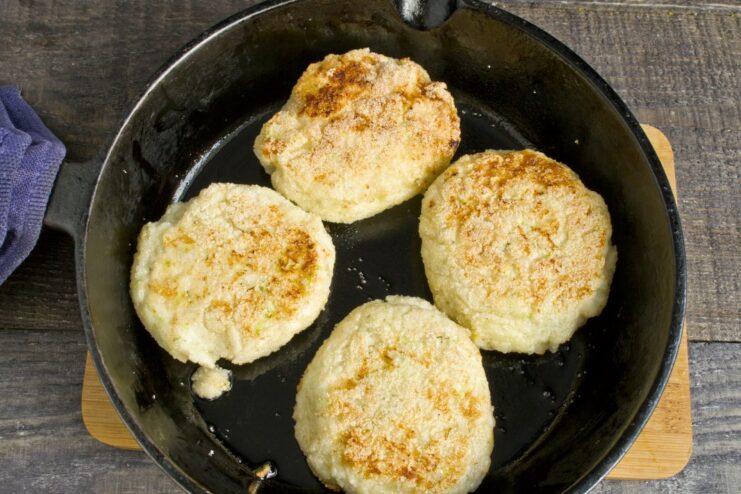 Frying the chicken patties until golden brown on each side. Golden-brown chicken patties sizzling in a hot frying pan.