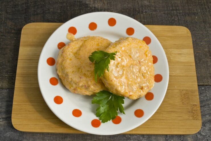 The finished dish: Tender chicken and zucchini patties ready to be served. A close-up shot of the finished chicken patties with zucchini, simmering in the sauce in a pan.