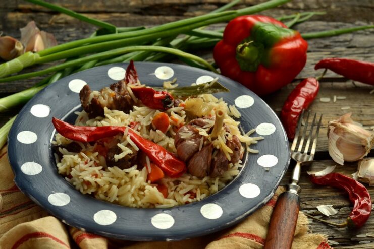 A plate of freshly cooked homemade lamb plov, garnished with herbs.