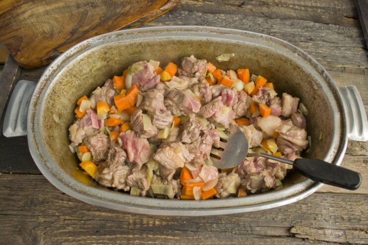 Vegetables and lamb frying in a large pot, the first stage of making plov.