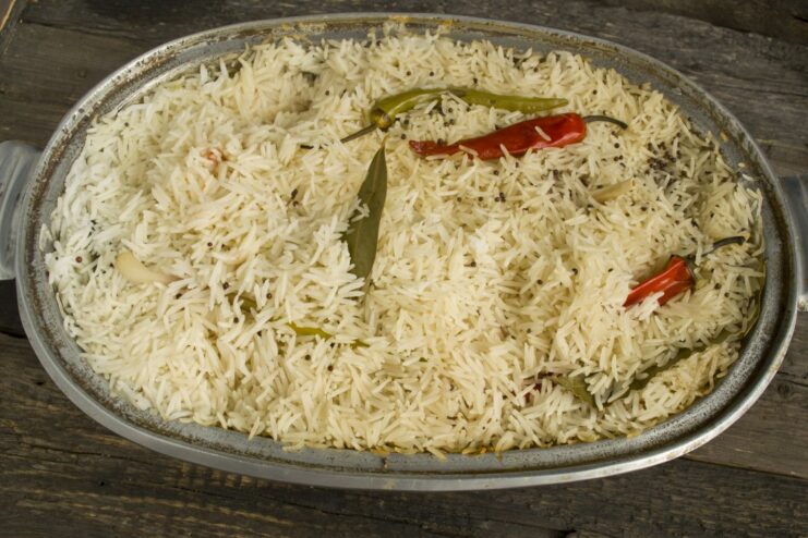 Plov simmering in a pot on the stove, covered with a lid.