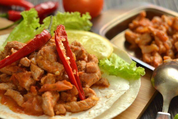 Delicious homemade Pork Fajitas served in a warm tortilla A plate of ready-to-eat pork fajitas wrapped in a tortilla with fresh greens.