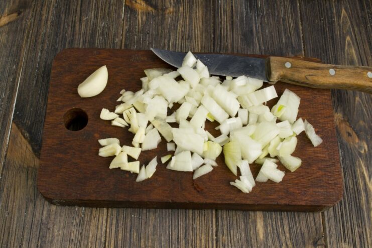 Sautéing finely chopped onion and garlic in olive oil until translucent Chopped onion and garlic being sautéed in a hot frying pan.