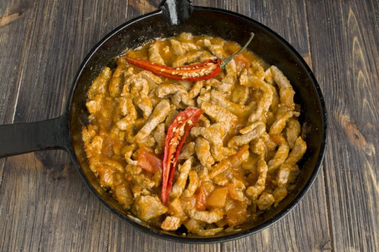 Simmering the pork fajita filling to let the flavors meld together The pork fajita filling simmering in a pan with rich tomato sauce.
