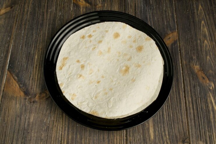 Warming up a flour tortilla on a dry pan until soft with light brown spots A flour tortilla being warmed on a dry frying pan for the fajitas.