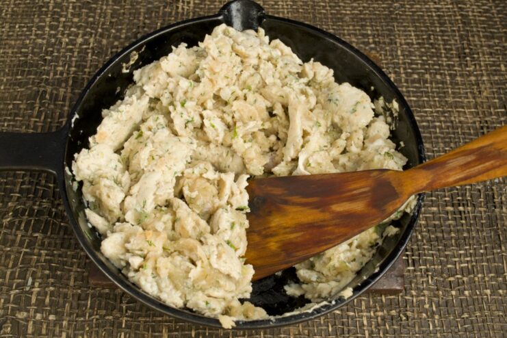 Lightly browning the chicken filling in a pan Ground chicken filling being sautéed in a frying pan until lightly cooked.