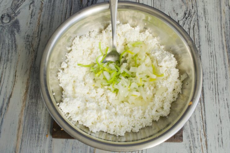 A bowl of sifted tvorog with sautéed onions being added.