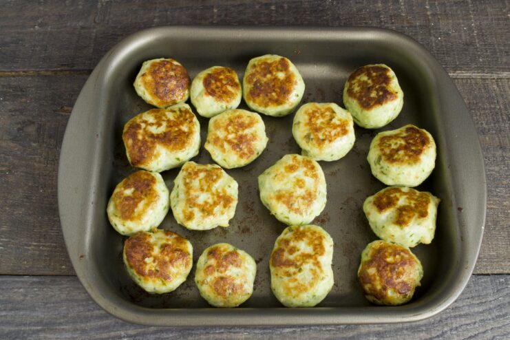 Golden-brown baked meatballs on a baking sheet just out of the oven.
