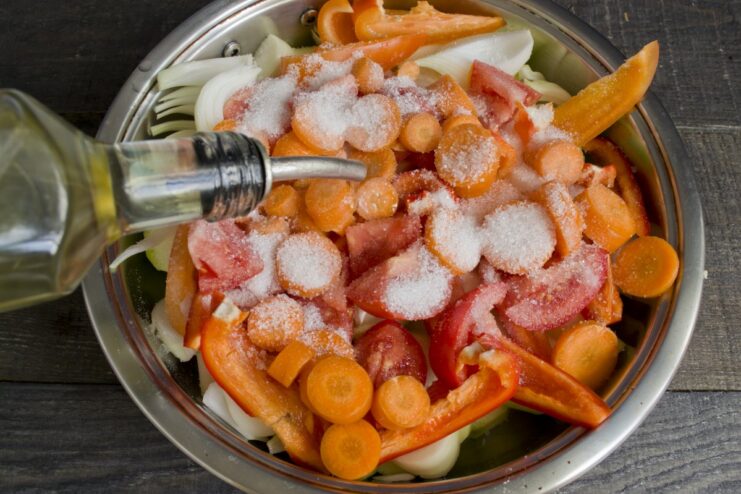 Seasonings like salt, sugar, and paprika being added to the chopped vegetables in the pan.
