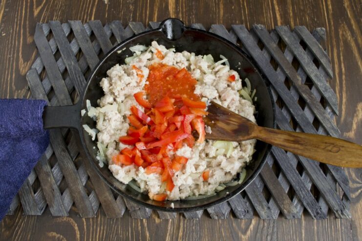 Adding finely chopped red bell pepper to the meat sauce Chopped red bell pepper being added to the skillet with the meat sauce.