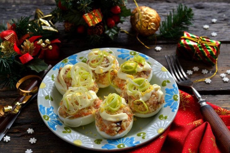 A plate of deviled eggs with herring and processed cheese, garnished with herbs.