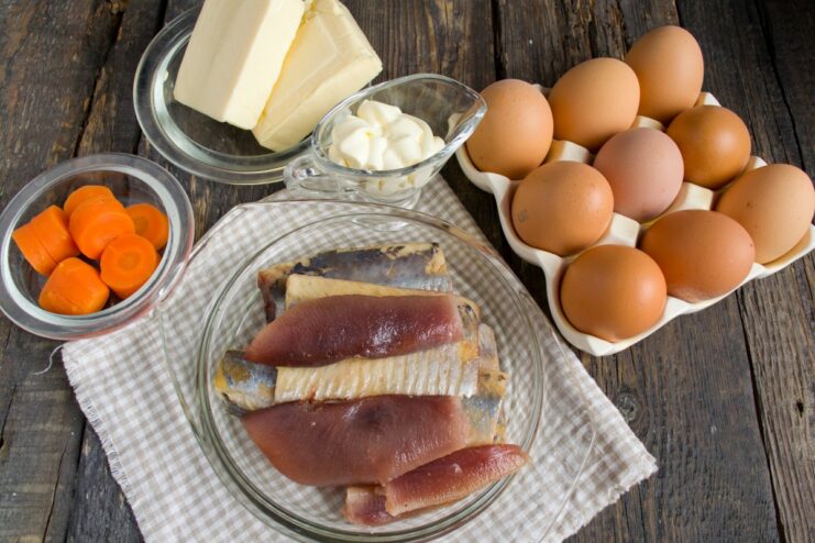 All the ingredients needed for the herring stuffed eggs recipe Ingredients for deviled eggs with herring laid out: eggs, herring, processed cheese, carrot, mayonnaise.