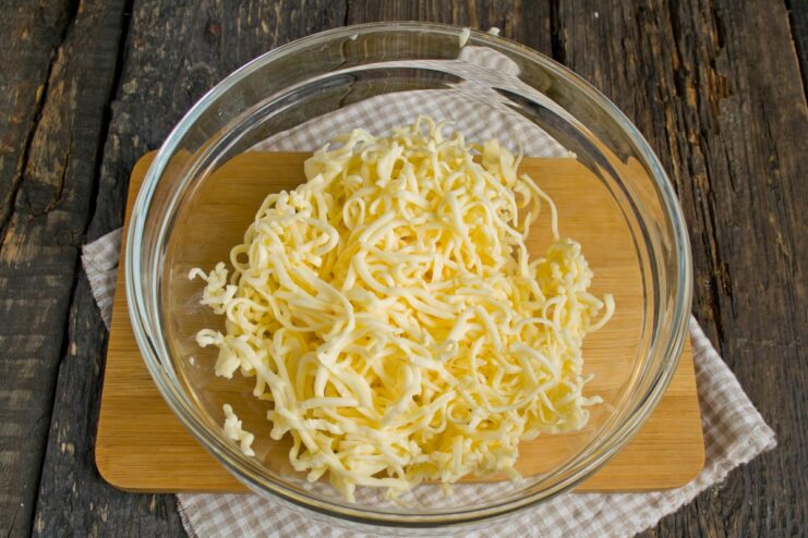 Pro Tip: Freeze processed cheese for easy grating A block of frozen processed cheese being grated on a fine grater.