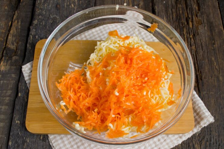 Adding grated carrot for color and sweetness A boiled carrot being grated on a fine grater into a bowl.
