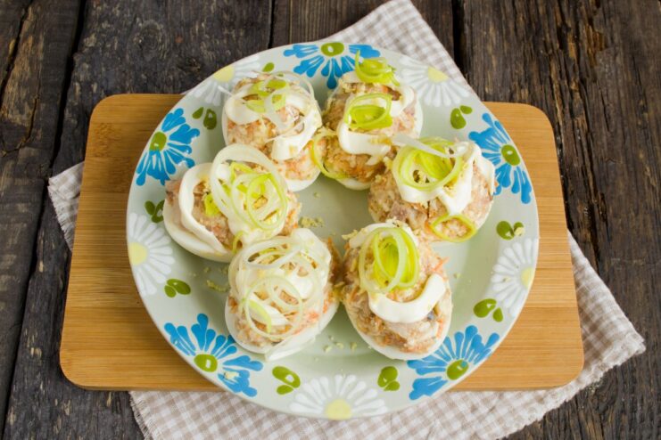 Final touch: Garnishing the deviled eggs before serving Finished deviled eggs with herring garnished with mayonnaise lines and chopped green onions.