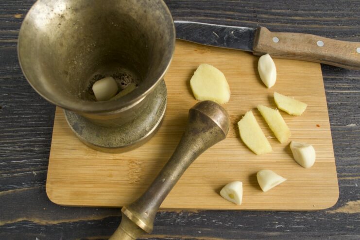 Creating a fragrant paste of ginger and garlic in a mortar to infuse the meat filling with deep flavor. A paste of ginger and garlic being added to the minced meat mixture in the skillet.