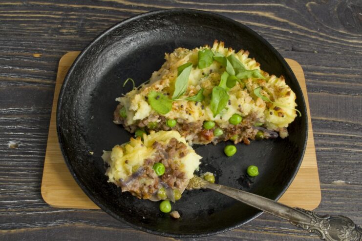 The finished Potato Pie, a perfect comfort meal for any occasion. A close-up of the finished potato pie with minced meat and vegetables, garnished with fresh herbs.