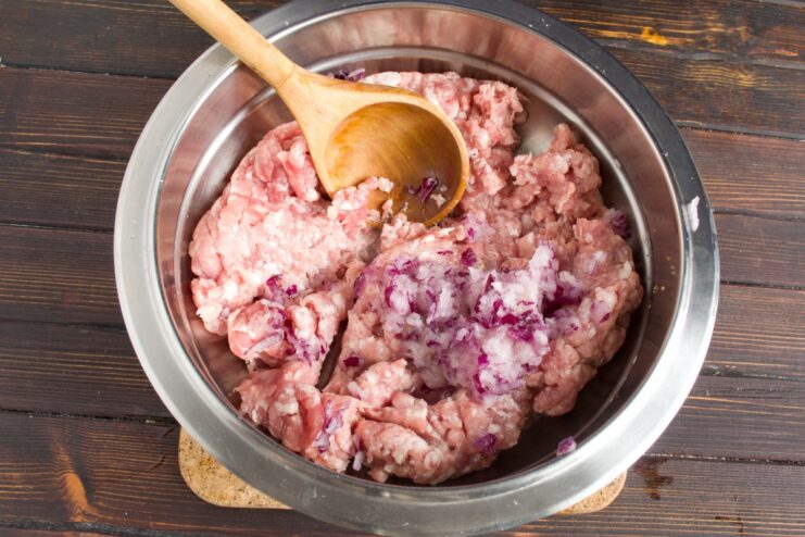 Preparing the Ground Meat Base for Cutlets A bowl of ground meat being mixed with grated onion for the cutlet recipe.